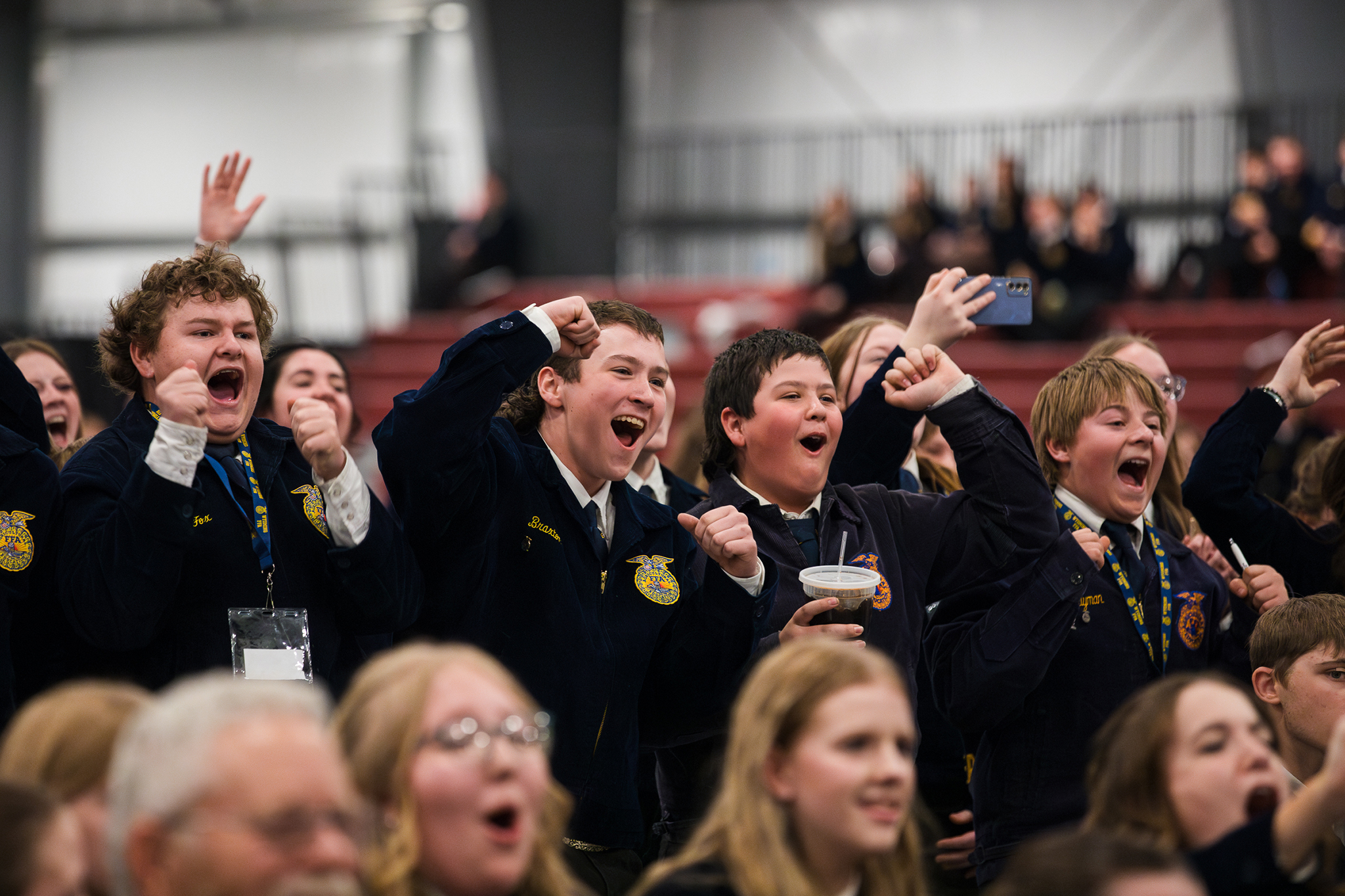 FFA members cheer and raise their fists from the bleachers during a lively moment at the Wyoming FFA State Convention, reacting to an on-stage announcement.