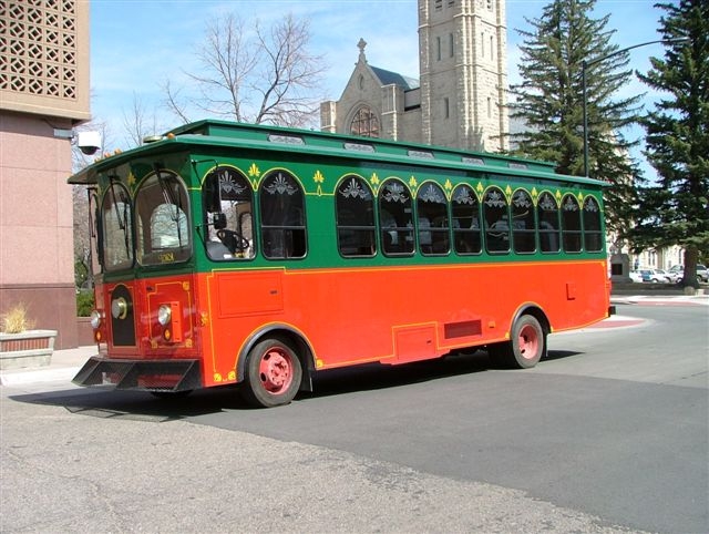 A red and green Tour Cheyenne trolley waits on a street