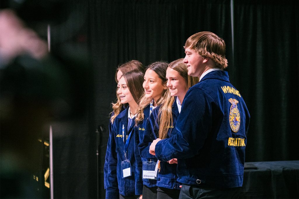 Four FFA members look at an unseen audience while receiving an award on stage