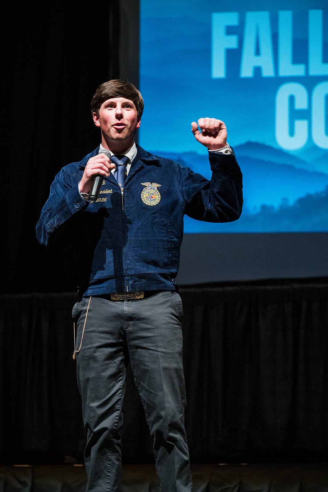 Wyoming FFA state officer speaks on stage at Fall Leadership Conference while holding a microphone.