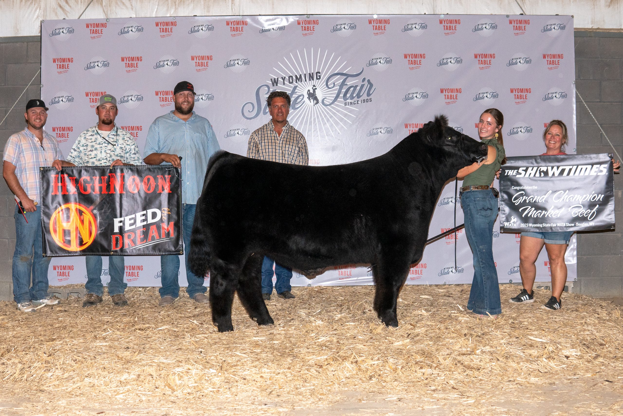 Livestock exhibitor showing a Grand Champion market beef with supporters and banners at the Wyoming State Fair.